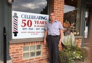 Marty Flint poses in front of Excalibur Barber Shop during 50th anniversary.